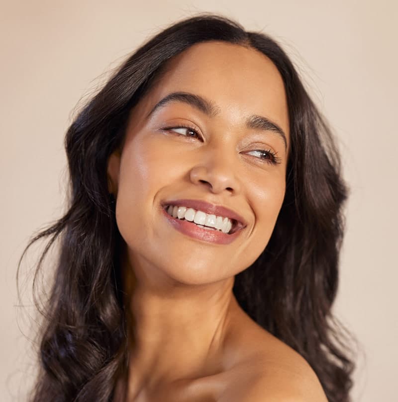 Woman with a radiant smile looking upwards, her dark curly hair framing her face.