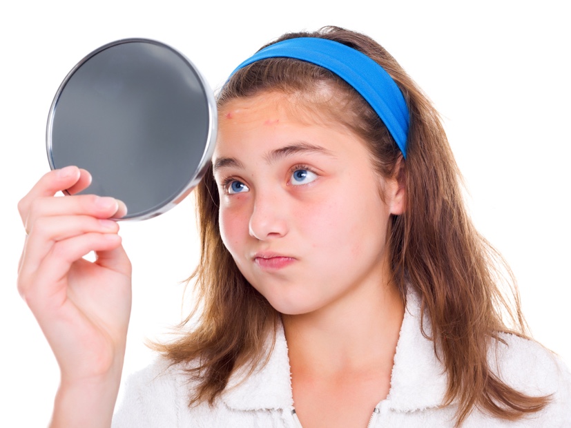 young girl looking at her skin in the mirror